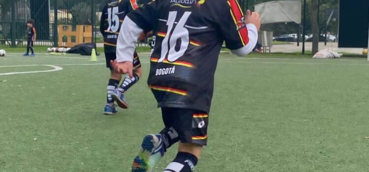 Aprende a jugar fútbol desde temprana edad en Bogotá. Niño corriendo durante el entrenamiento de fútbol infantil en la cancha sintética de El Salitre, Bogotá