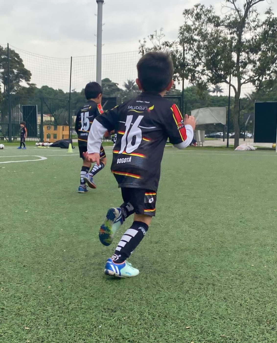 Niño corriendo durante el entrenamiento de fútbol infantil en la cancha sintética de El Salitre, Bogotá